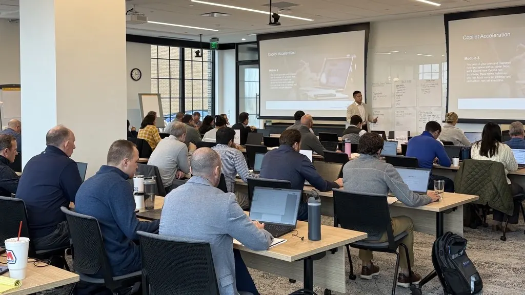 Rows of professionals at laptops in a bright training room
