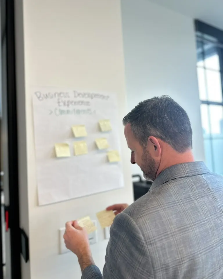 An attendee reading sticky-note commitments on a flip chart