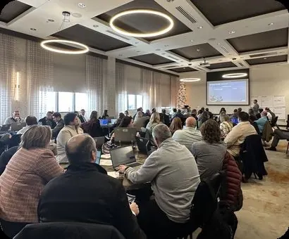 A ballroom of attendees working on laptops during a live session